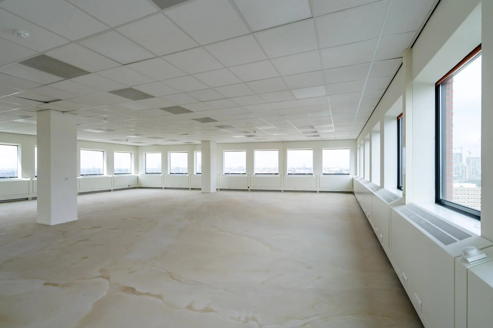 Licht en leeg kantoorpand met grote ramen aan het Johanna Westerdijkplein.